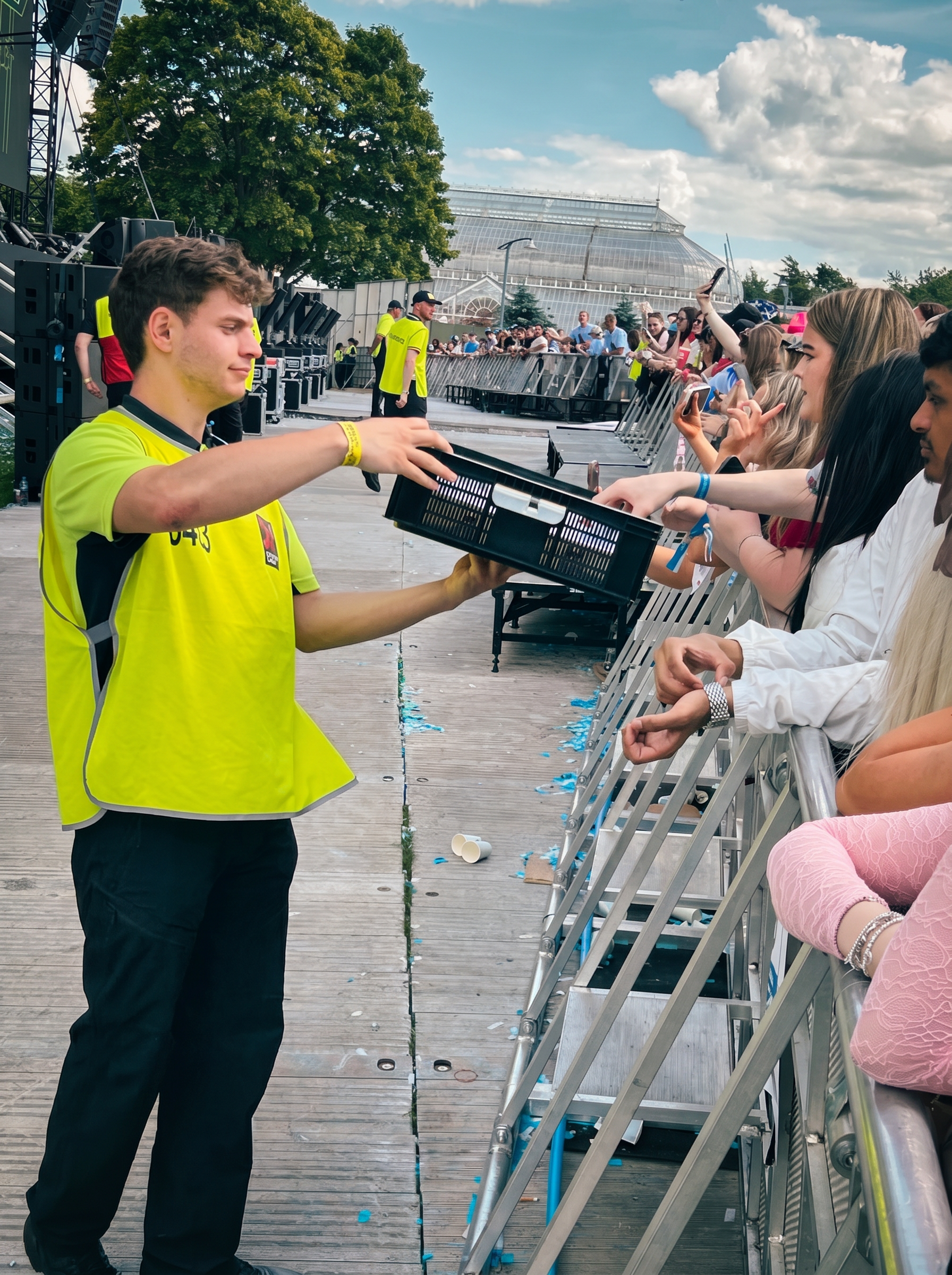 PitWater steward passing a tray of pre-filled water cups to fans at the front-of-stage barrier