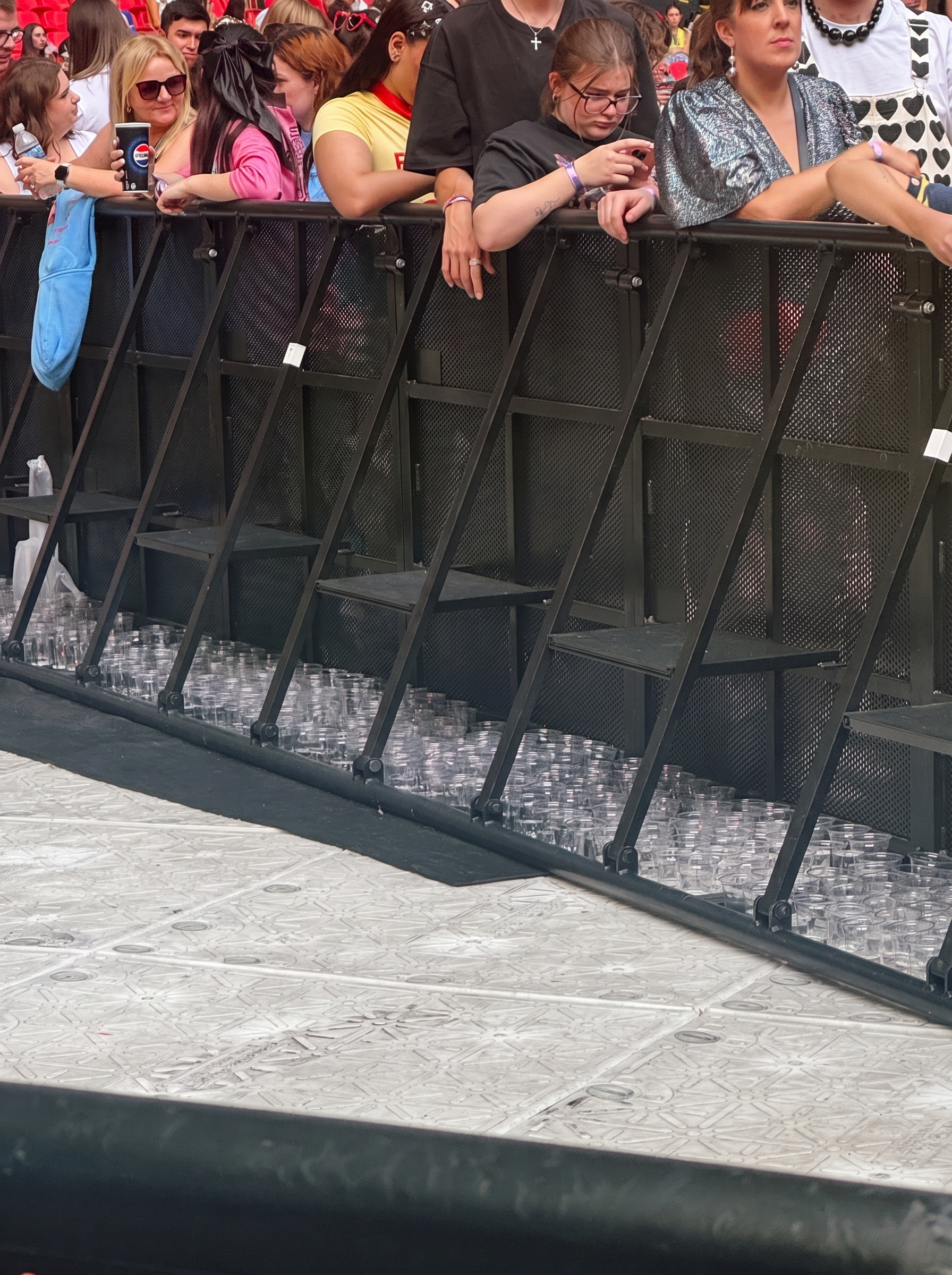 Rows of empty plastic cups pre-loaded on the ground behind a front-of-stage barrier