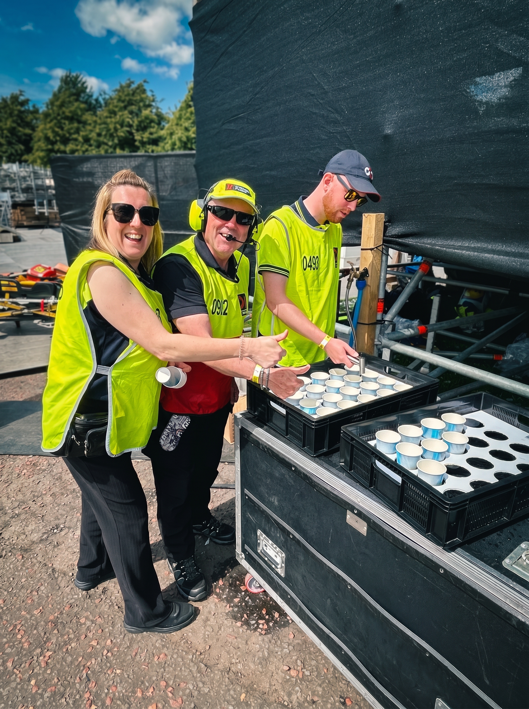PitWater team filling paper cups from the station tap, trays loaded and ready to run to the pit